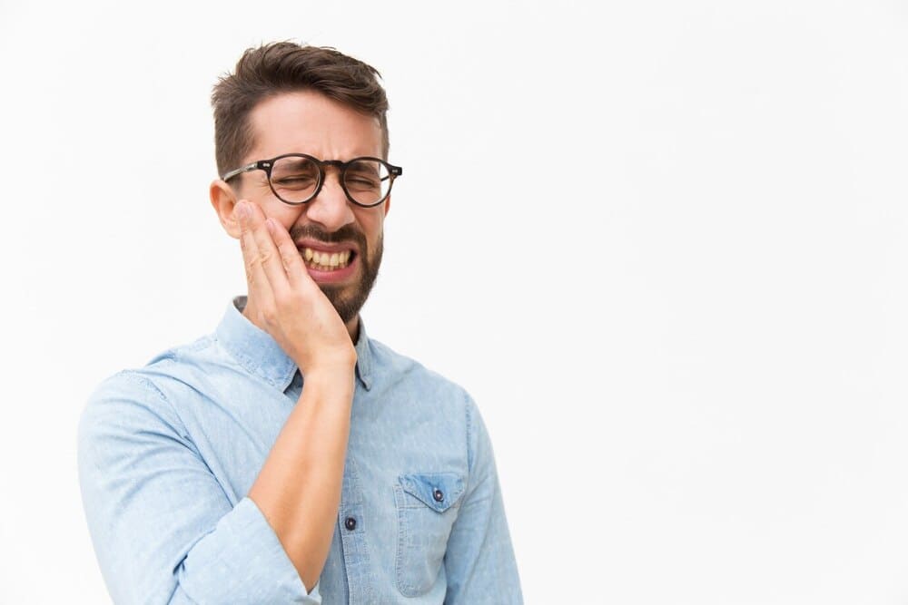 chico con mano en mejilla dolor por problema dental chico con mano en mejilla dolor por problema dental